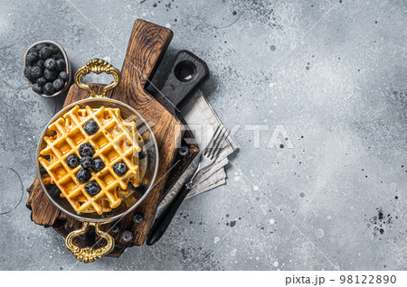 Fresh Belgian waffles with blueberry and Syrup in skillet. Gray background. Top view. Copy space 98122890