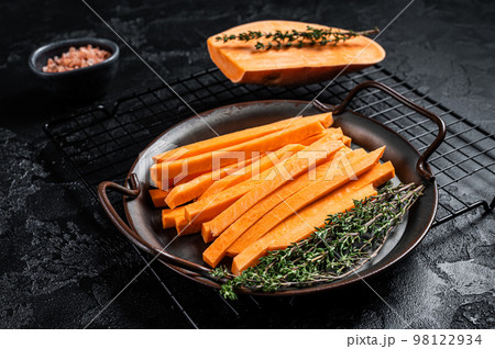 Sliced Sweet potatoes in a steel tray, fresh batata fries ready for cooking. Black background. Top view Sliced Sweet potatoes in a steel tray, fresh batata fries ready for cooking. Black background. Top view 98122934