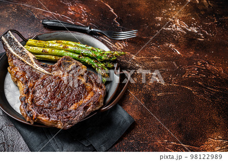 BBQ Grilled Tomahawk or Cowboy with bone beef steak, roasted asparagus. Wooden background. Top view. Copy space 98122989