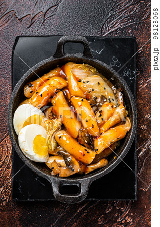 Korean Topokki or Tteokbokki rice cake with egg and mashrooms. Dark background. Top view Korean Topokki or Tteokbokki rice cake with egg and mashrooms. Dark background. Top view 98123068