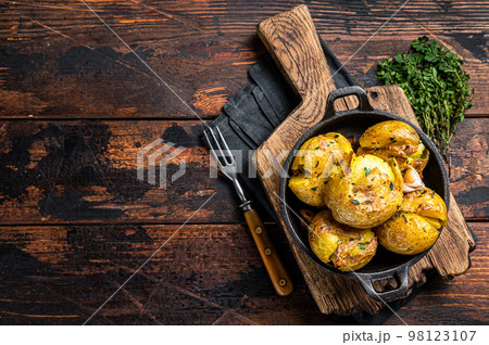 Crushed, Broken potatoes baked in oil with herbs. Wooden background. Top view. Copy space 98123107