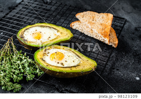 Cooking Baked Avocado with Egg. Black background. Top view Cooking Baked Avocado with Egg. Black background. Top view 98123109