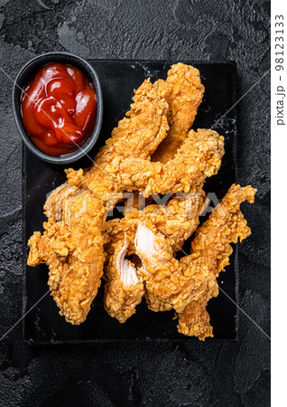 Breaded chicken strips Fingers with Ketchup. Black background. Top view 98123133