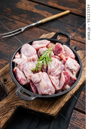 Raw chicken giblets gizzards, stomachs in a skillet ready for cooking. Wooden background. Top view 98123334