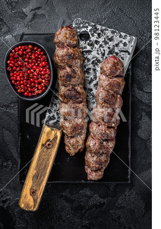 Urfa kebab, ground beef and lamb meat grilled on skewers. Black background. Top view 98123445