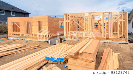 Wooden frame of two new houses with engineered lumber materials in front 98123745