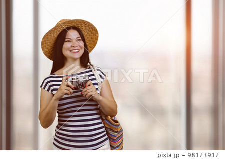Portrait of happy asian cheerful female tourist with vintage photo camera. Indoor blurred window background. Portrait of happy asian cheerful female tourist with vintage photo camera. Indoor blurred window background. 98123912