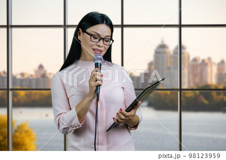 Business woman with a microphone and clipboard. Checkered windows background. 98123959