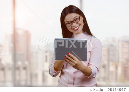 Portrait of smiling young asian businesswoman with glasses. Indoor windows bacgkground. Portrait of smiling young asian businesswoman with glasses. Indoor windows bacgkground. 98124047