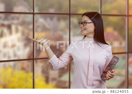 Young asian businesswoman holding tablet pc and showing copy space. Autumn streetscape background. 98124055