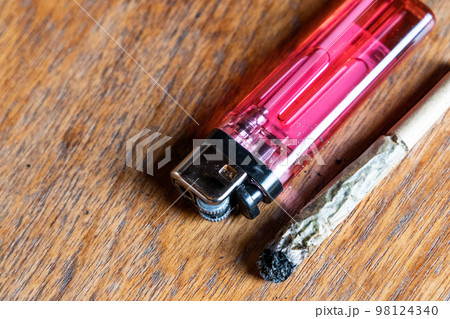 Spent cannabis cigarettes with lighter on wooden table Spent cannabis cigarettes with lighter on wooden table 98124340
