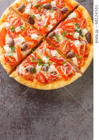 Fresh Homemade Vegetarian Greek Pizza with feta and vegetables closeup on the wooden board. Vertical top view 98124501