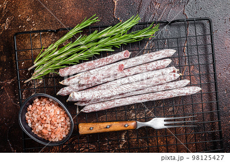Fuet Catalan dry sausages with rosemary. Dark background. Top view 98125427