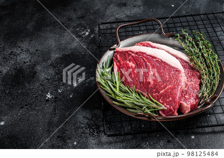 Raw top sirloin or Picanha beef meat steak in a steel tray. Black wooden background. Top view. Copy space Raw top sirloin or Picanha beef meat steak in a steel tray. Black wooden background. Top view. Copy space 98125484