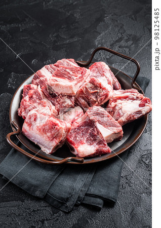 Raw diced beef and lamb marbled meat in kitchen steel tray. Black background. Top view Raw diced beef and lamb marbled meat in kitchen steel tray. Black background. Top view 98125485