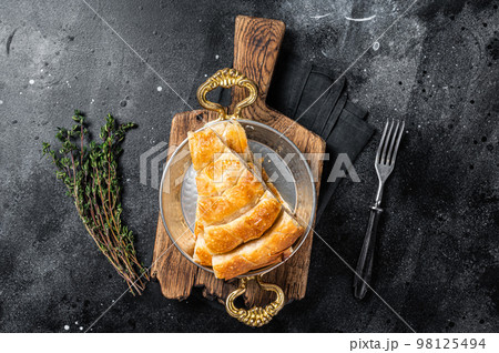 Traditional feta cheese phyllo pastry pie in rustic skillet. Black background. Top view Traditional feta cheese phyllo pastry pie in rustic skillet. Black background. Top view 98125494
