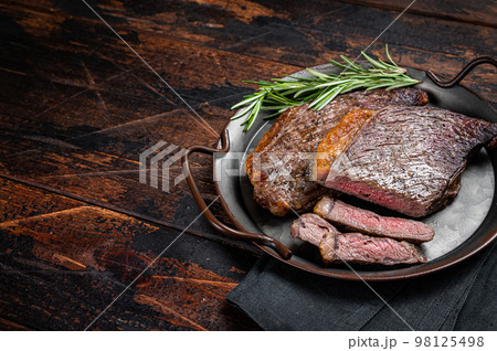 Grilled picanha or top sirloin beef steak with rosemary in steel tray. Wooden background. Top view. Copy space 98125498