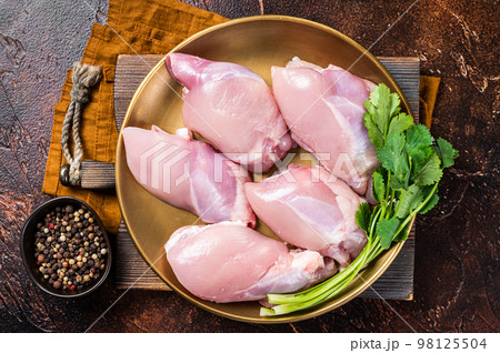 Free range Raw Boneless and skinless Chicken leg thigh fillet with spices. Dark background. Top view Free range Raw Boneless and skinless Chicken leg thigh fillet with spices. Dark background. Top view 98125504