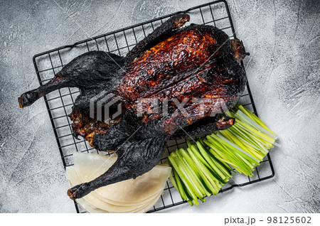 Whole roast Peking duck with herbs, sauce, rice Pancake, Cucumber and onion. White background. Top view 98125602