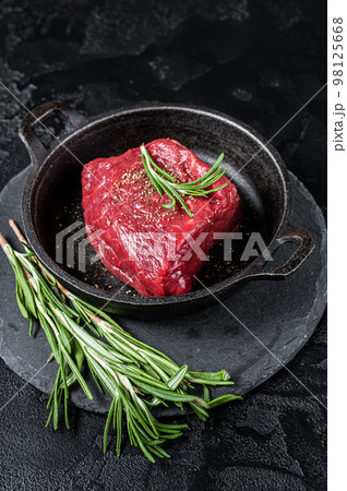 Fresh Raw sirloin rump steak in a skillet with herbs. Black background. Top view 98125668