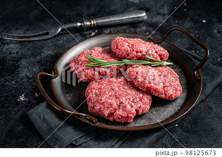 Uncooked Frikadellen from Mince beef Meat, raw meat cutlets. Black background. Top view 98125673
