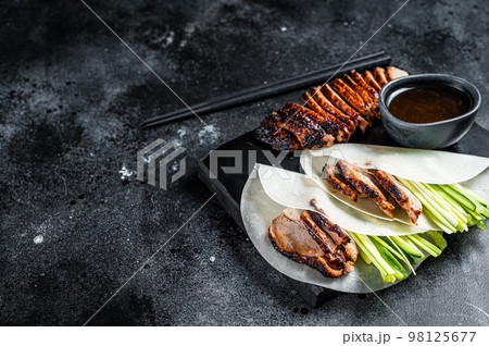 Traditional served Peking Duck with cucumber, green onion, in wheaten chinese pancakes. Black background. Top view. Copy space Traditional served Peking Duck with cucumber, green onion, in wheaten chinese pancakes. Black background. Top view. Copy space 98125677