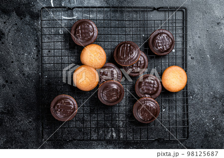 Jaffa Cakes, Cookies covered with dark chocolate and filled with orange marmalade. Black background. Top view 98125687