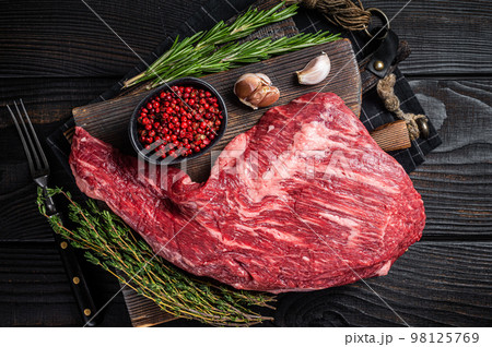 Tri Tip black angus beef steak on cutting board with herbs, raw meat. Black Wooden background. Top view 98125769
