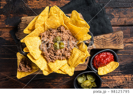Mexican Baked nachos with chili con carne in a skillet. Wooden background. Top view Mexican Baked nachos with chili con carne in a skillet. Wooden background. Top view 98125795