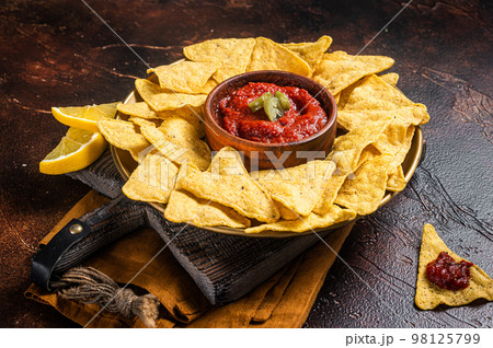 Nachos chips with tomato sauce and jalapeno, mexican appetizer. Dark background. Top view 98125799