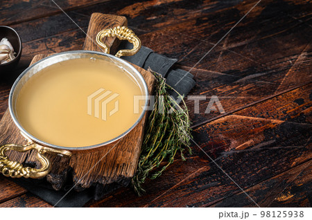 Clear broth stock without meat in cooking skillet. Wooden background. Top view. Copy space 98125938