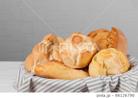 Fresh italian wheat breads in the basket on white wall background. Fresh italian wheat breads in the basket on white wall background. 98126790