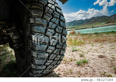 4x4 car mud tire on off road close-up. 4WD SUV car traveling on wild nature 4x4 car mud tire on off road close-up. 4WD SUV car traveling on wild nature 98127164