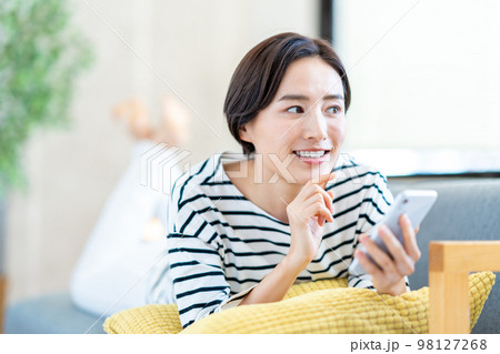 ソファーでスマホを操作する女性 98127268