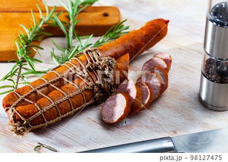 Sliced half-smoked sausages on wooden table 98127475