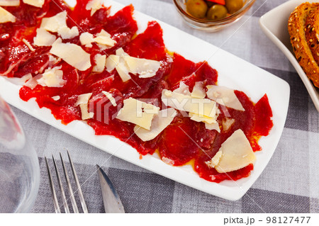 Appetizing raw veal carpaccio served with cheese 98127477