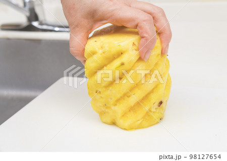 【皮削ぎの終わったパイナップルを切っていく】 98127654