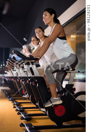 Woman on stationary bike workout in gym 98128201