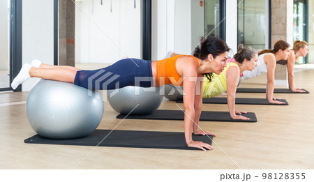 Women exercising with ball during group pilates class 98128355