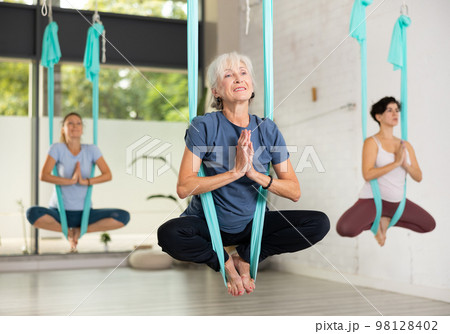 Sporty women are warming up before doing aerial yoga Sporty women are warming up before doing aerial yoga 98128402