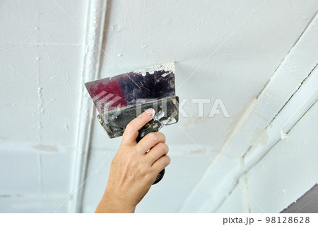 Painter putty ceiling defects using spatula for painting. Painter putty ceiling defects using spatula for painting. 98128628