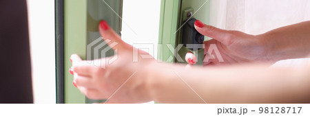 Woman closes or opens glass doors to balcony Woman closes or opens glass doors to balcony 98128717