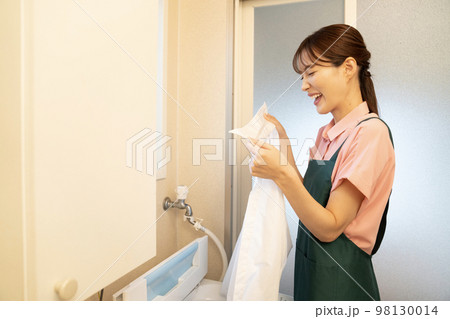 洗濯したシャツの襟を見て顔をしかめる女性 98130014