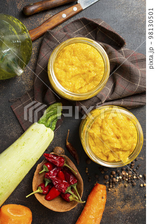 Delicious vegetable caviar in jars, thyme and purple basil on a table 98130501
