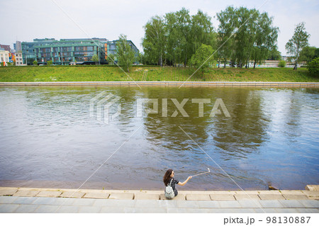 Beautiful girl sits and makes selfie near the river 98130887