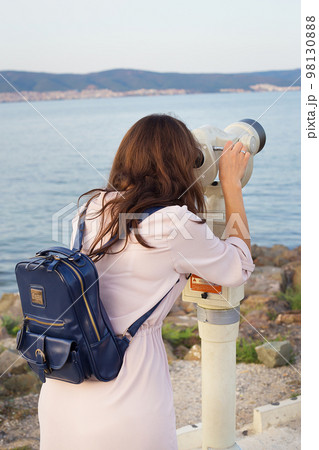 The girl looks through the telescope at the sea 98130888