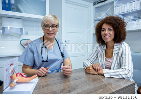 Expericenced gynecologist showing the anatomical model to junior colleague 98131156