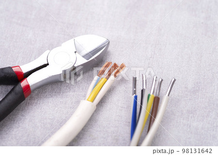 Electric cables without insulation and wire cutters on a gray table Electric cables without insulation and wire cutters on a gray table 98131642