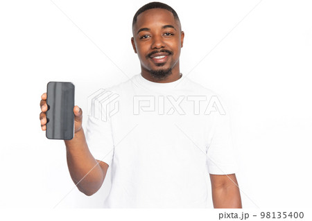 Joyful young man presenting smartphone Joyful young man presenting smartphone 98135400