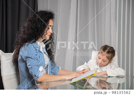 Nervous mother helps daughter with doing homework at home Nervous mother helps daughter with doing homework at home 98135562